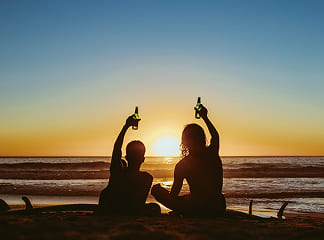 夕陽のビーチで乾杯する二人